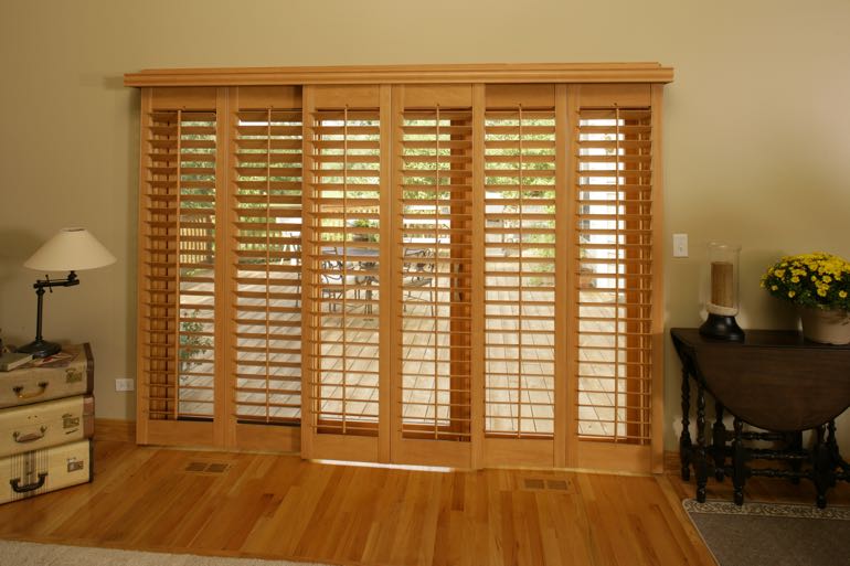 Wood shutters on sliding door going to outdoor porch.